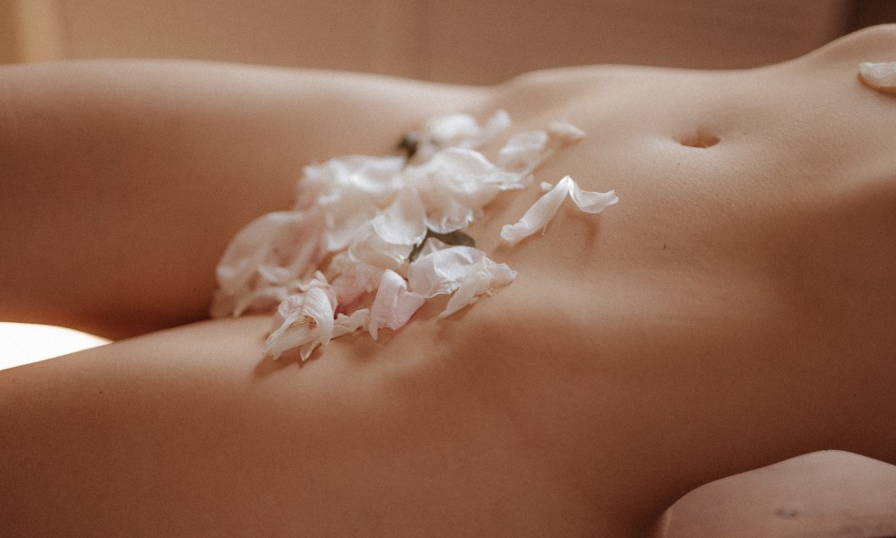 Naked woman with flower petals covering parts of her body