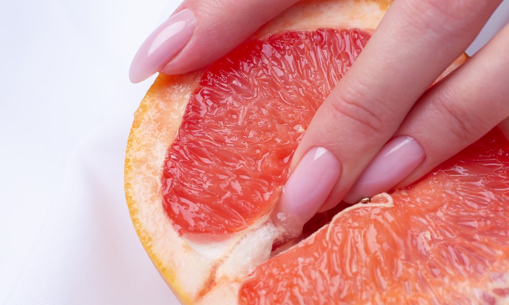 women's fingers in grapefruit
