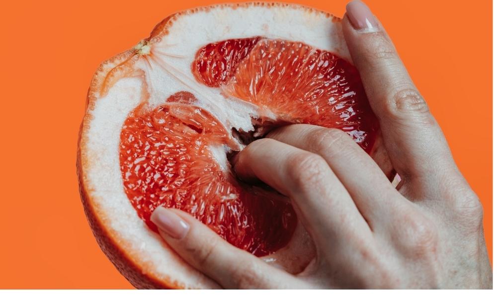 women's fingers in grapefruit