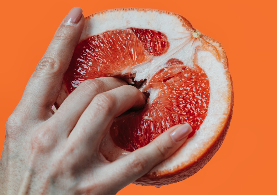 woman's fingers inside a fresh grapefruit